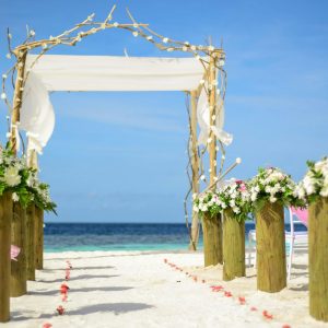 A beautiful beach wedding setup featuring a floral arch and ocean view.
