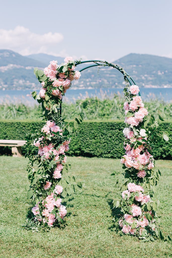 A pink floral arch set against a scenic mountain backdrop at an outdoor wedding venue.