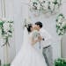 Bride and groom share a romantic kiss under a flower arch at their indoor wedding ceremony.