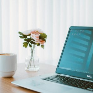 Comfortable home office desk with laptop, coffee mug, and flower vase.