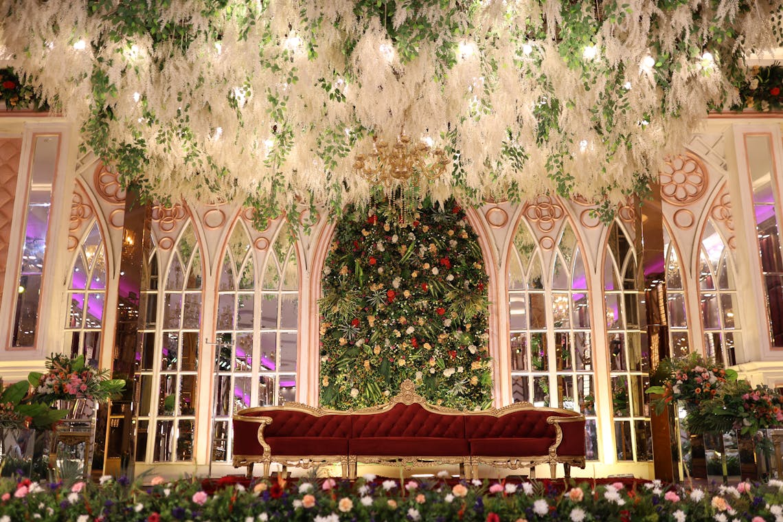 Elegant wedding venue with floral decor, arched windows, and plush furniture. Ideal for lavish events.